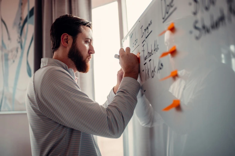 a man writing on a wall with some paper clips