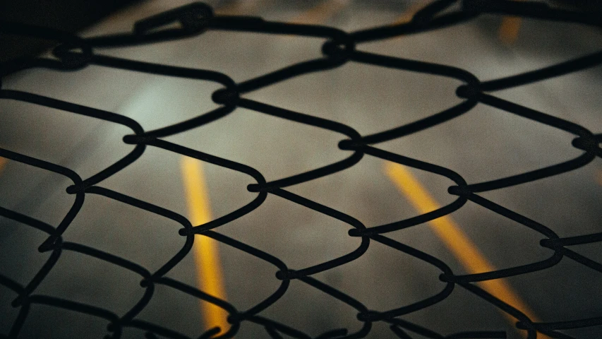 a black fence with a yellow stripe and lines through the mesh