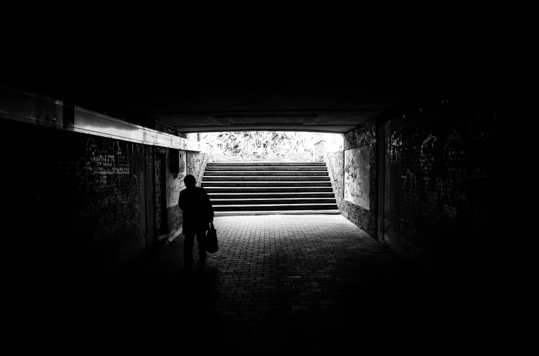 a man walking into a dark tunnel next to stairs