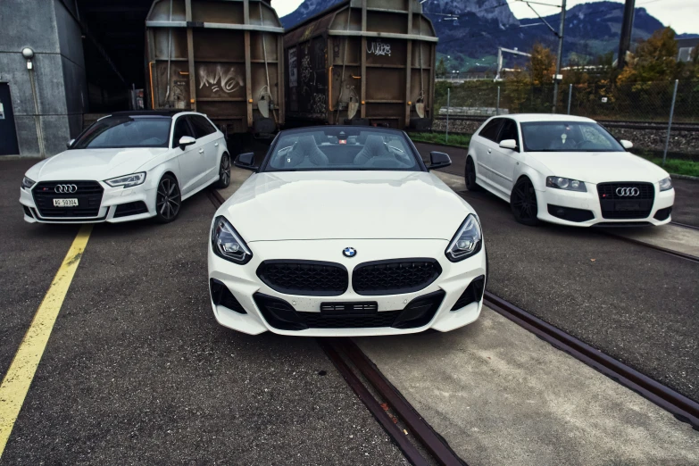 two white sports cars parked near each other on a city street