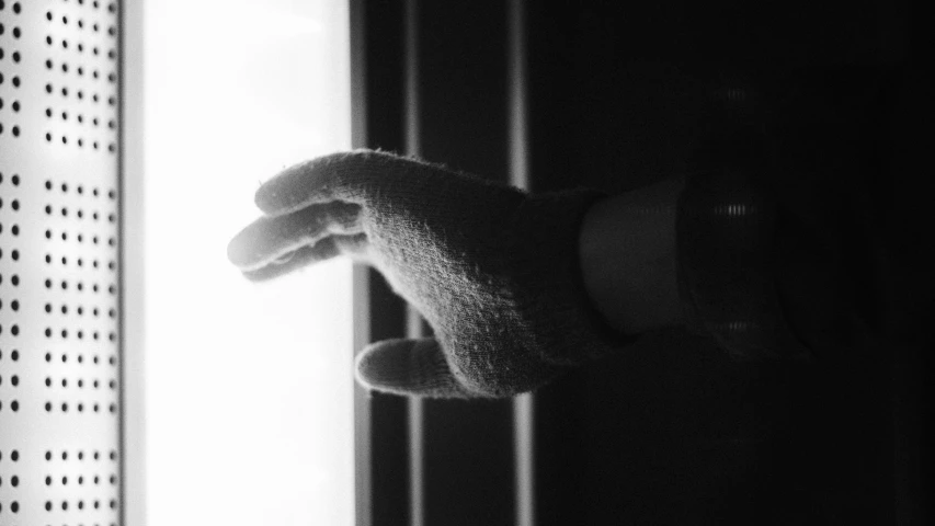 black and white pograph of someones hand with the bathroom door open