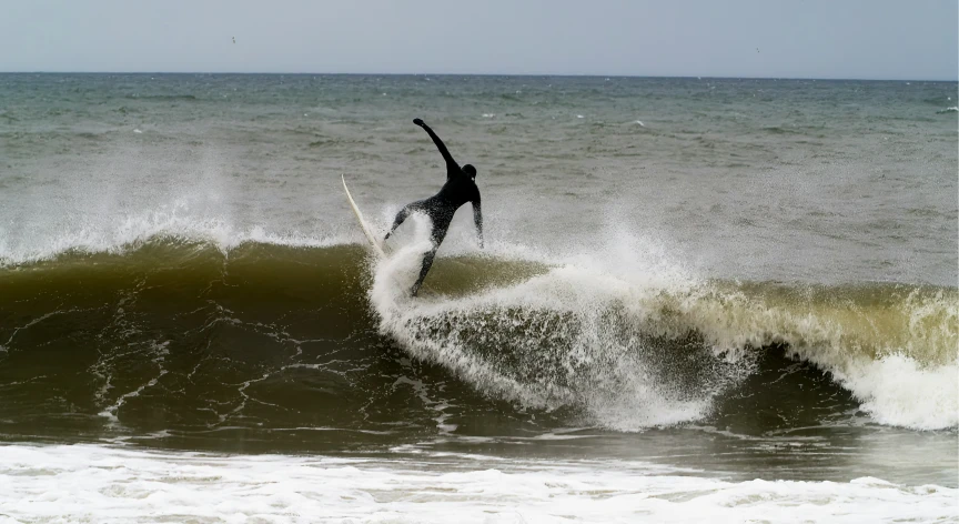 a person in black jacket surfing on wave with large ocean waves