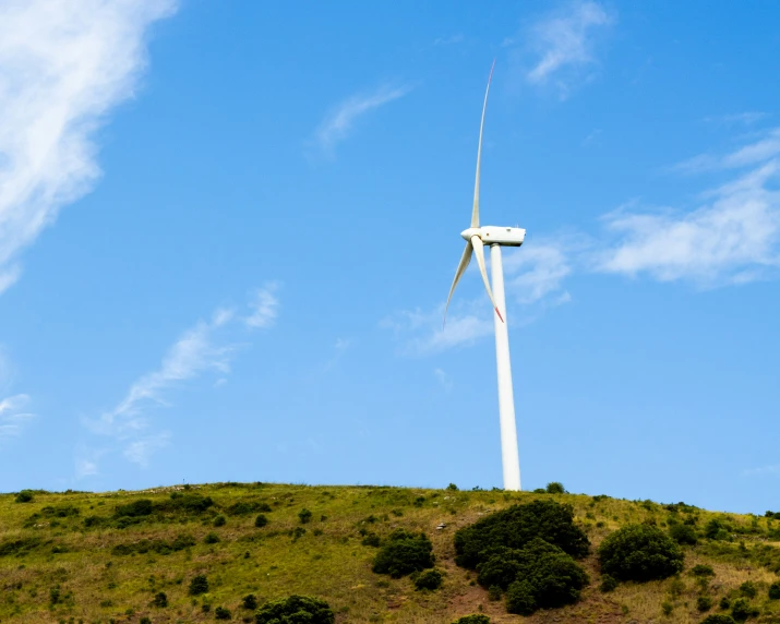 a wind turbine on a hill in a sunny day