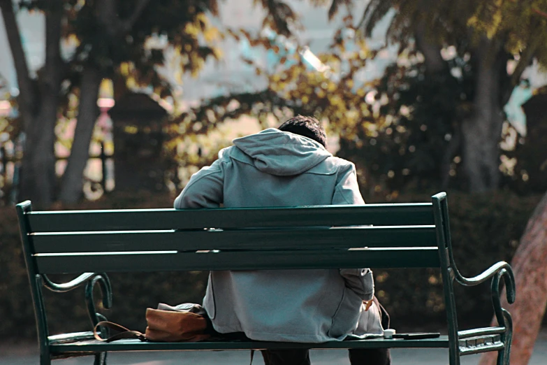 woman sitting on green park bench outside near trees