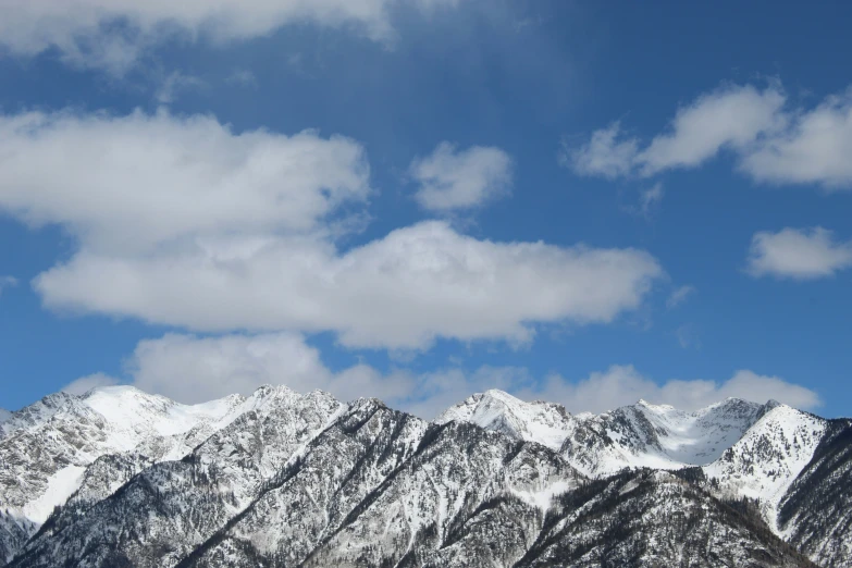 the snowy mountains are a backdrop of fluffy clouds