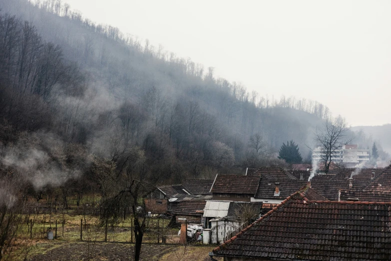 some houses in a rural setting with smoke coming out of the roofs