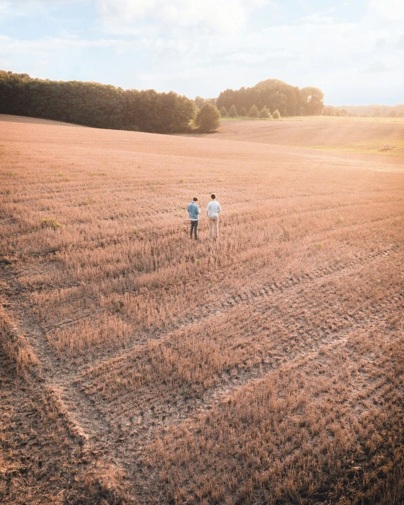 two people walking through an open field together