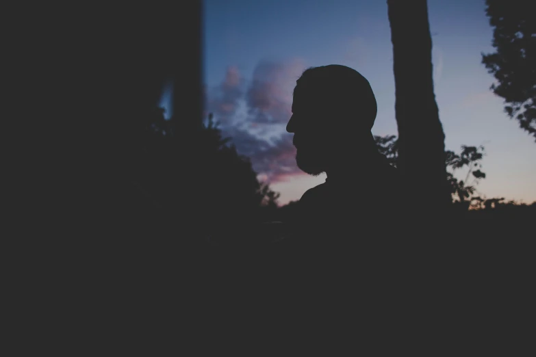 the silhouette of a man in the dark next to trees