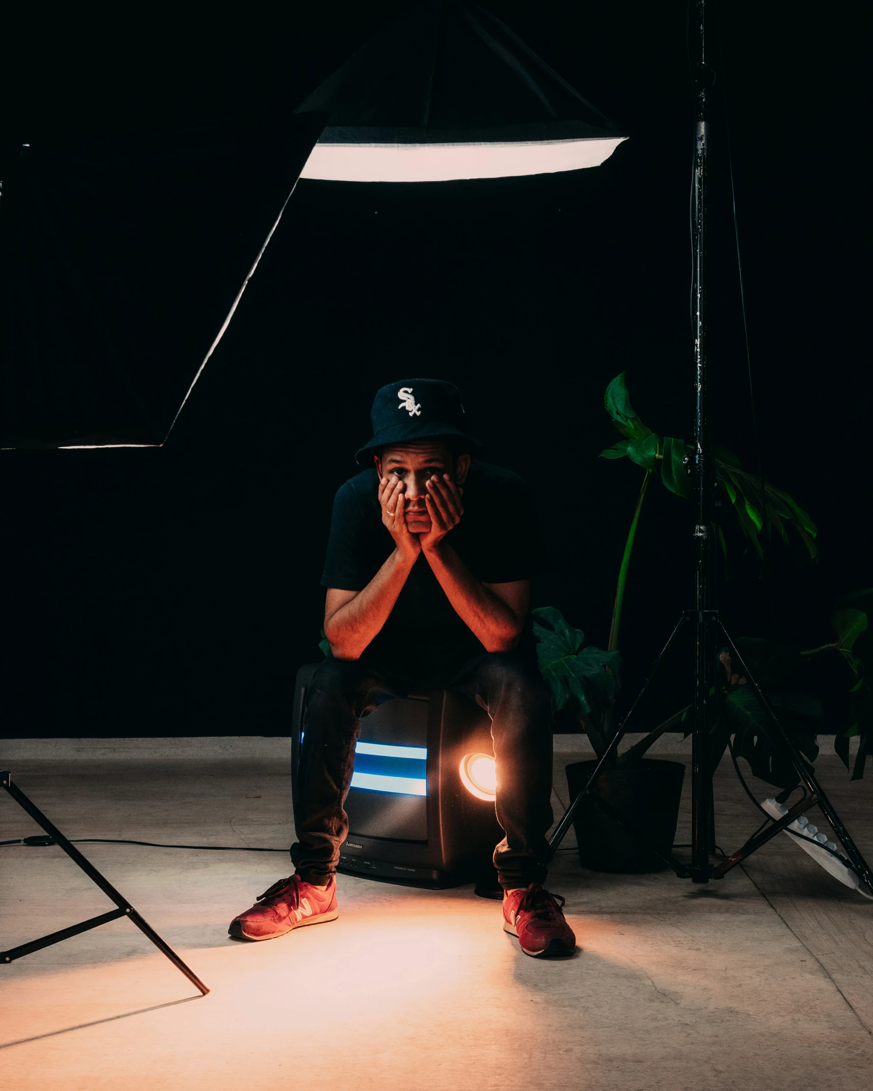 a young man sitting on the ground in front of a lamp