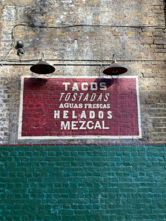 the sign is hanging up on a brick wall