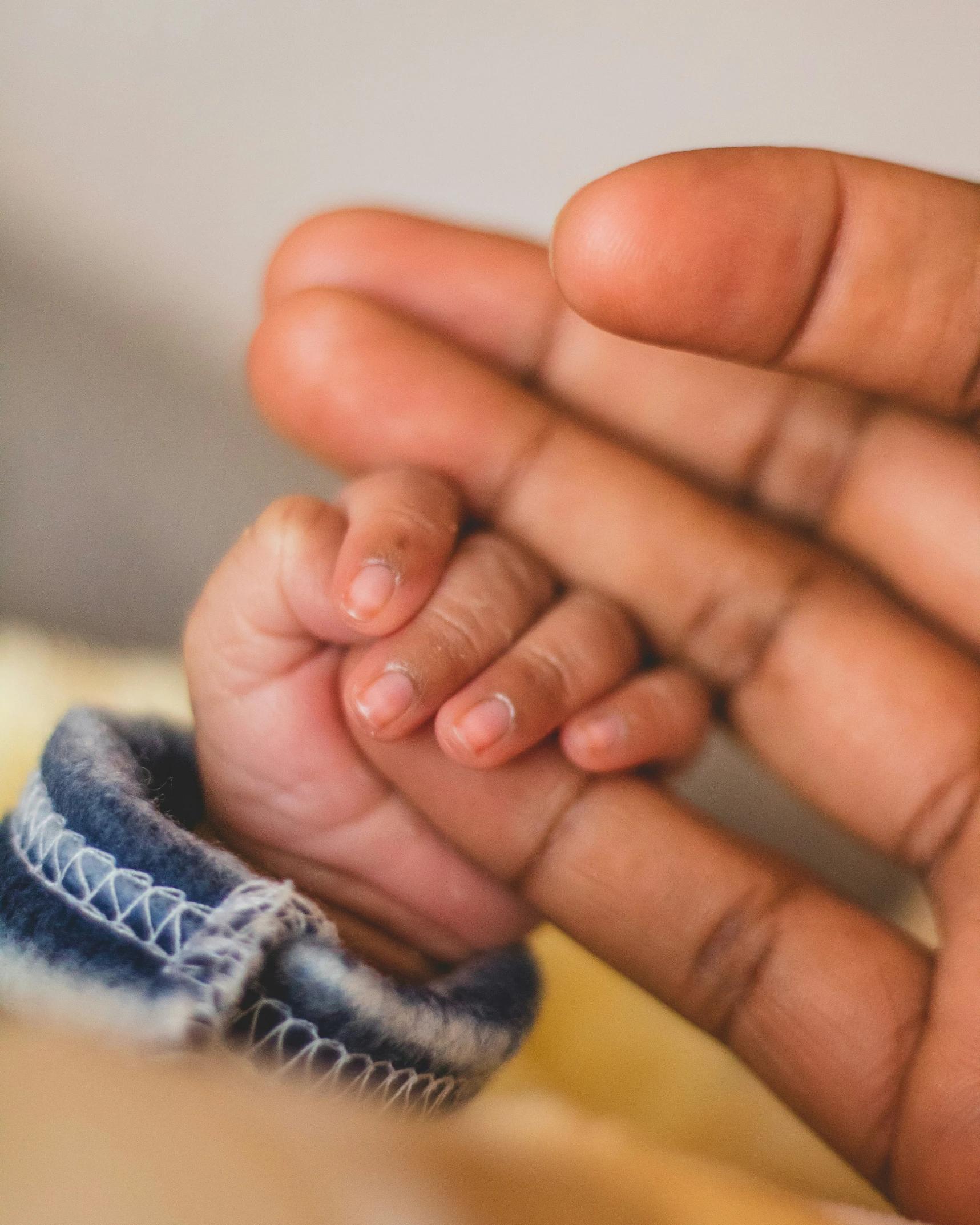 a close up of a baby's hand holding onto another infant