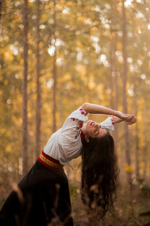 a woman standing in a forest while holding her head