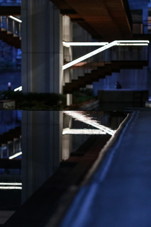 some lights are reflected in water below a bridge