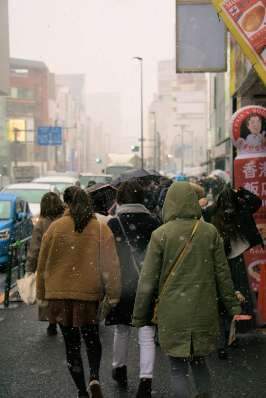 many people are walking in the snow with umbrellas
