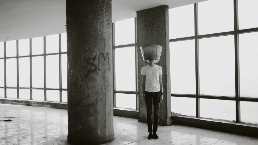 man wearing a mask standing in a very large room with windows