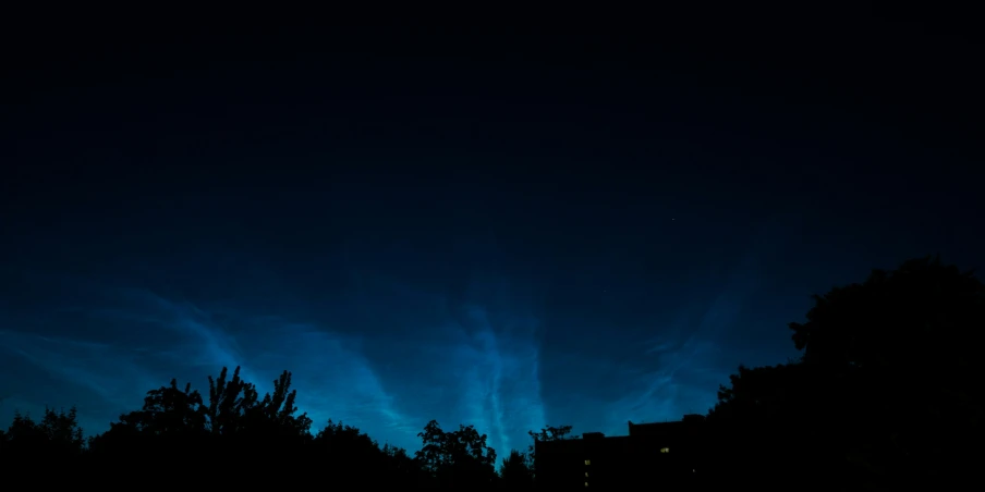 a dark blue sky at night with some white clouds in the distance