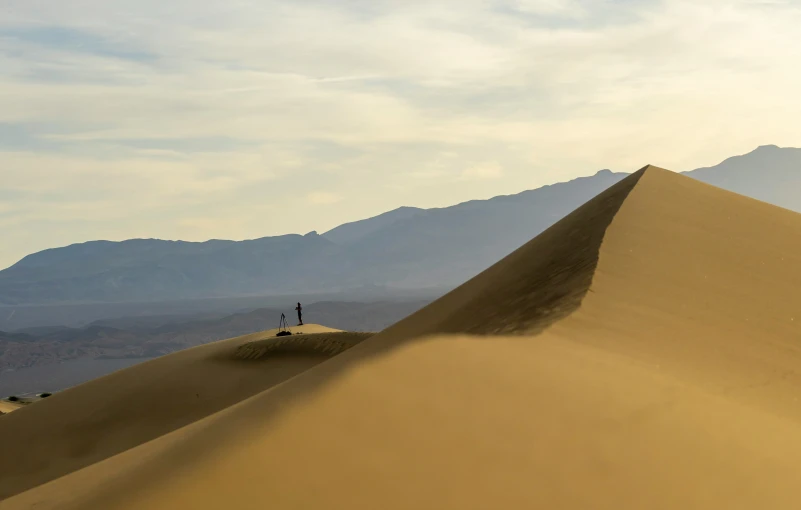 a lone person stands in the middle of a sand dune