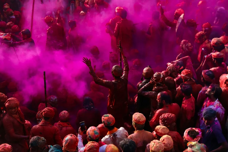 several people are dressed in red and purple while powder is thrown on them