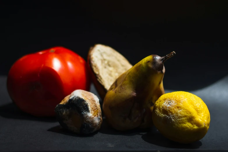 some fruit is laying on the table with an apple, tomato, and a banana