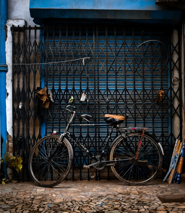 an antique bicycle leaned against a wall in front of a fence