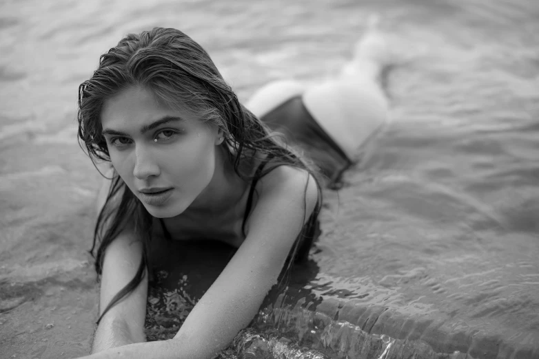 a girl wearing a short dress sitting on top of a surfboard in the ocean