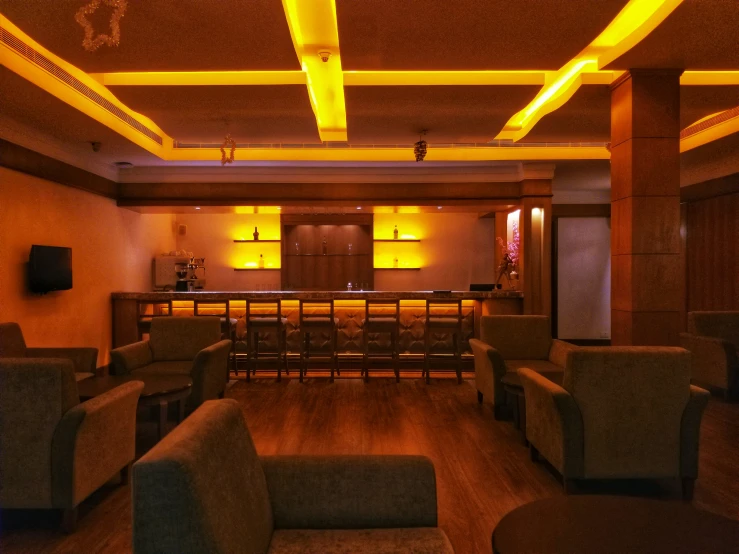 a well lit bar with brown furniture and wooden floors