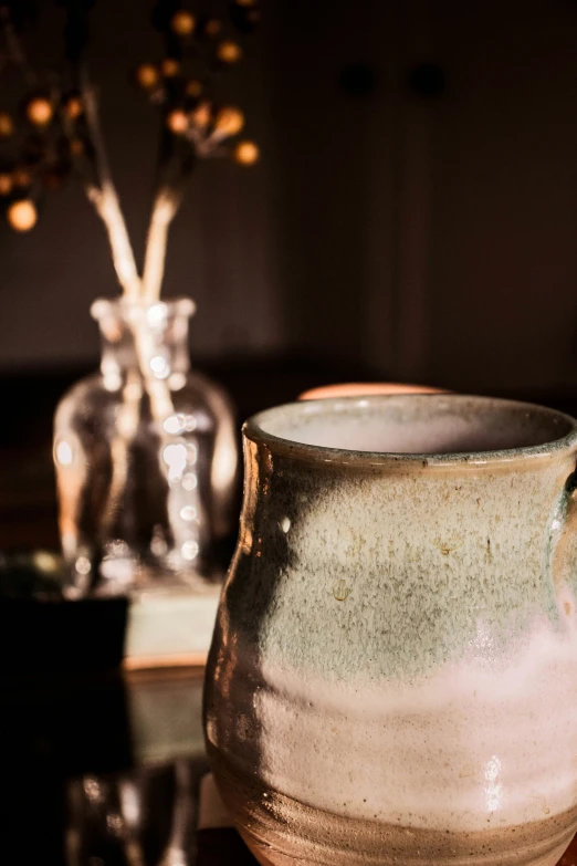 a vase on a table next to a candle