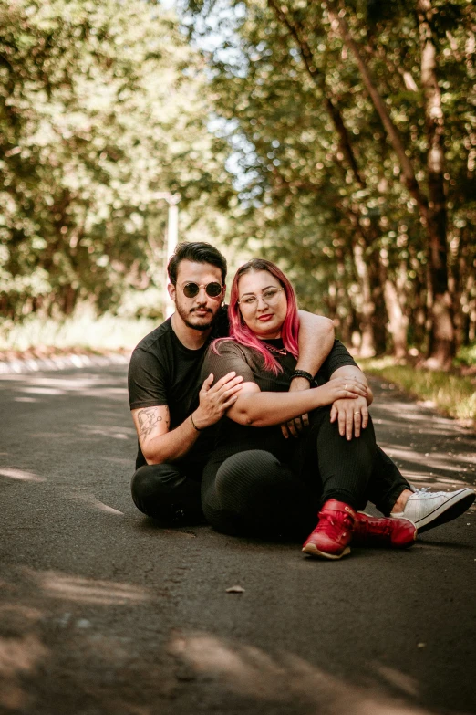 a young couple pose for a portrait in the woods