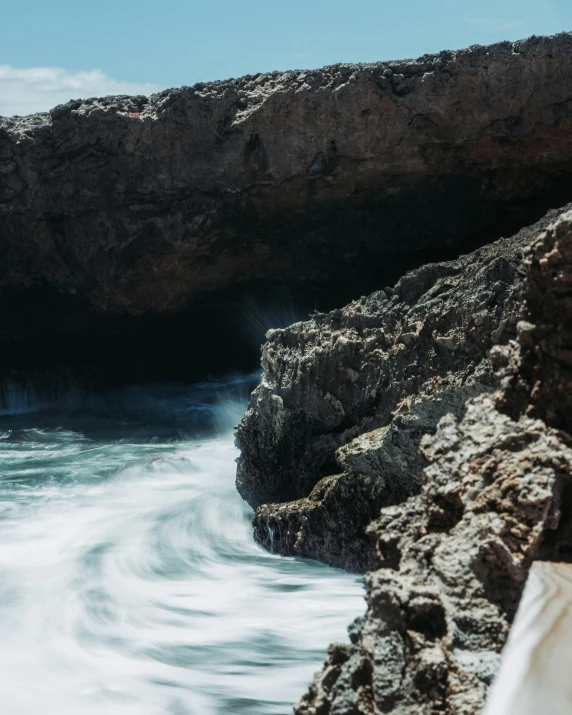 waves come up near rocks to the shore as a boat approaches