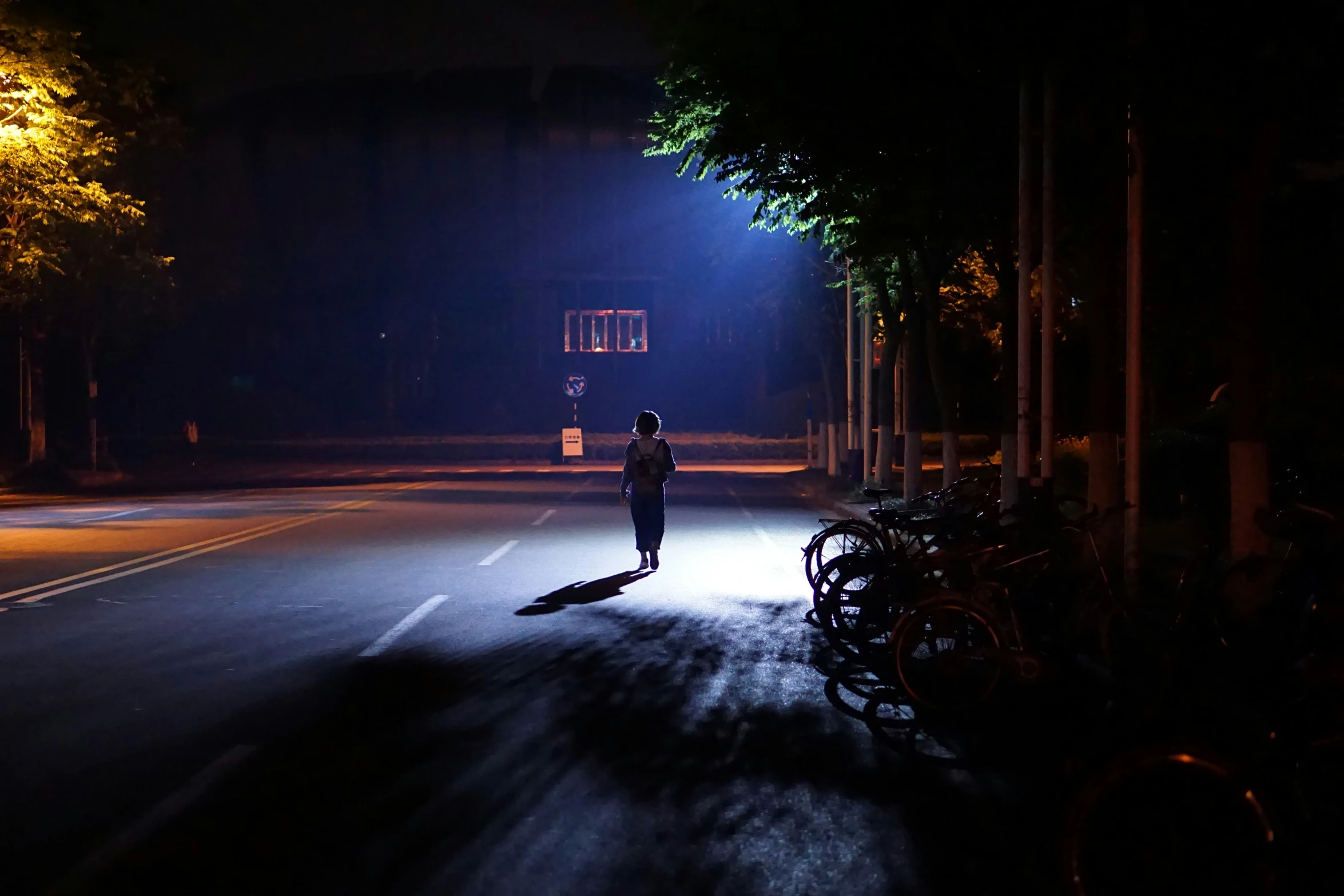 a woman walks down the street at night in the dark