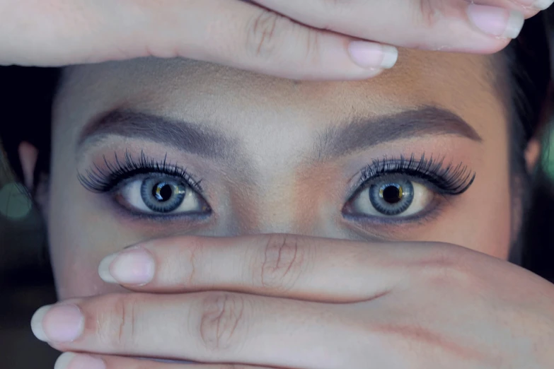 an attractive woman holds her hand up to her eye