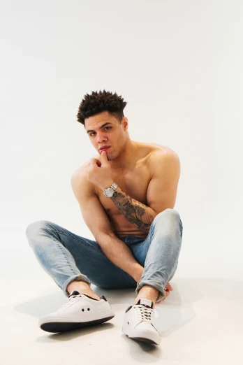 a man in jeans with a tattoo sitting on the floor