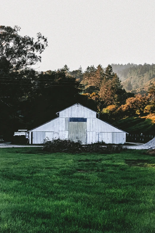 a white barn sits in the middle of a grassy field