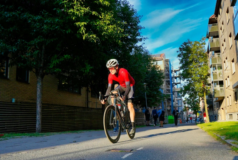 the man in the red shirt rides his bike down the street