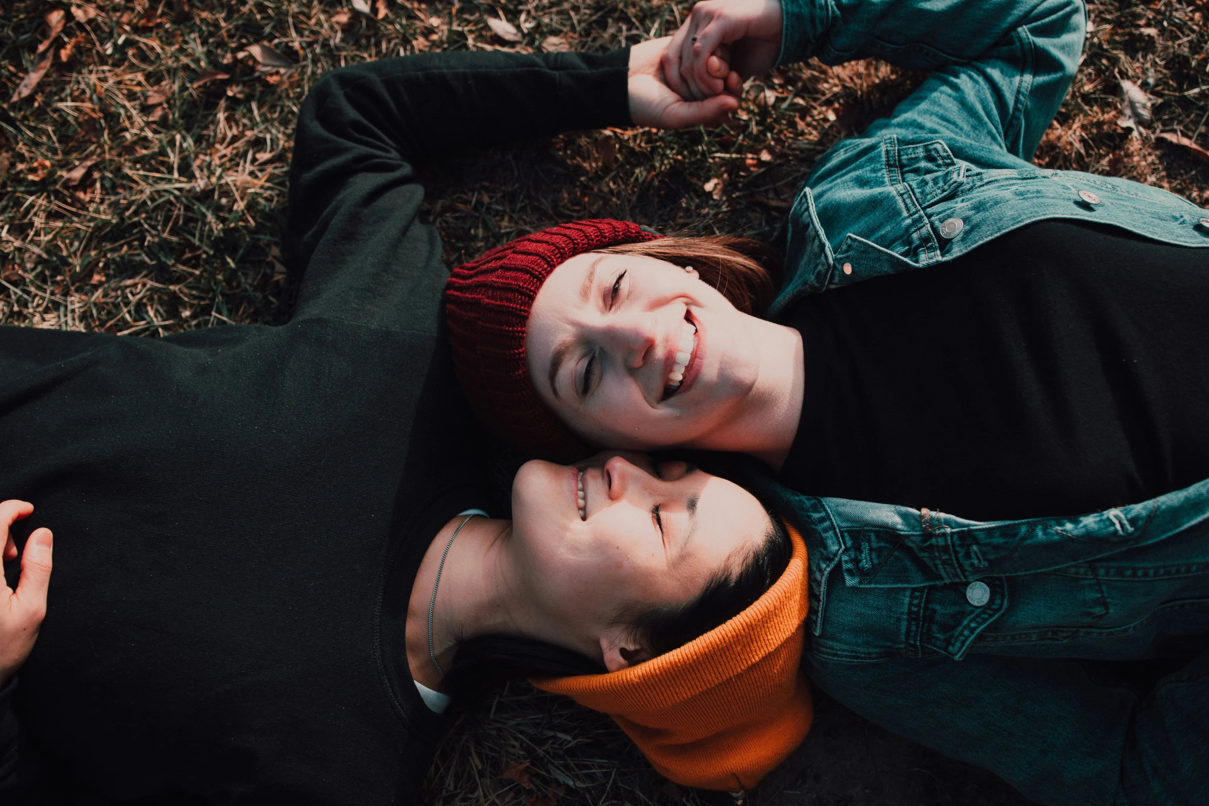 two smiling teenaged girls lying on ground