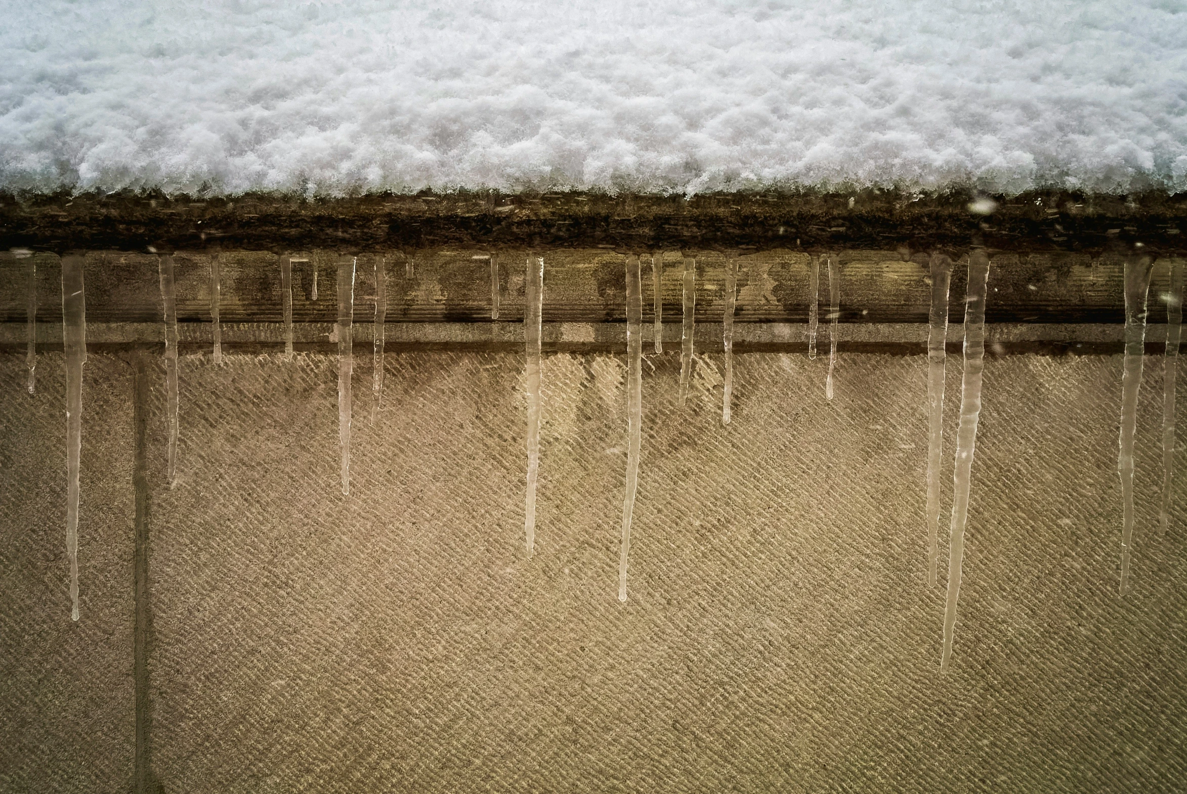 the snow is falling on top of trees and a fence