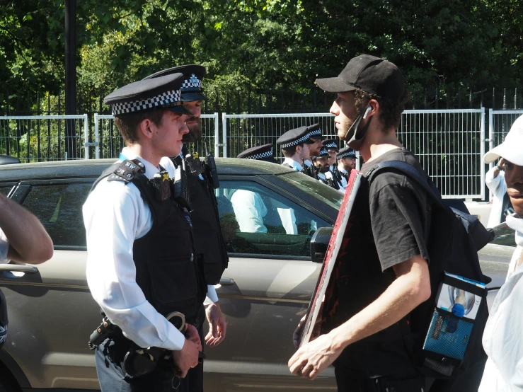 a couple of men are talking outside with police around