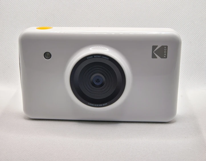 white digital camera laying down on table with lens