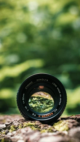 a small camera lens is shown sitting on a mossy rock