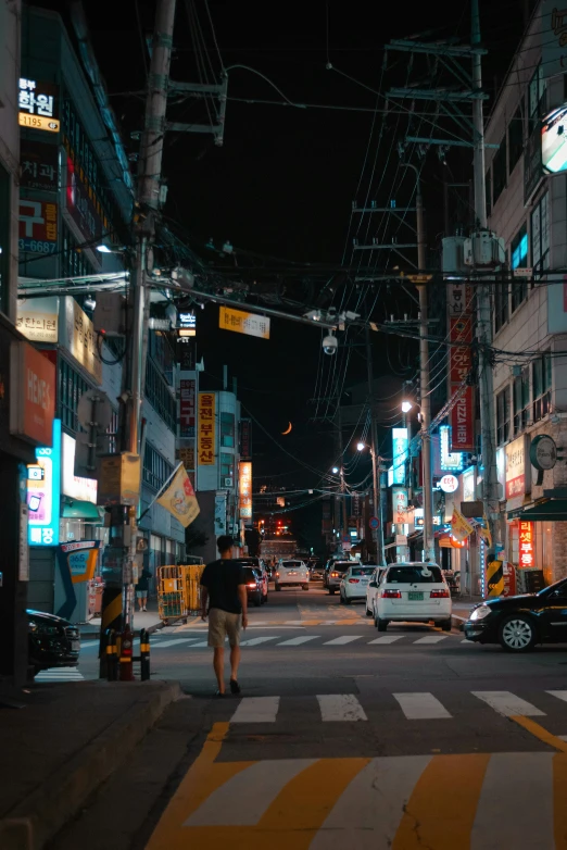 an intersection with cars, people and traffic signs at night