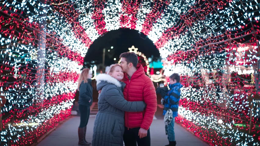 man and woman standing under lights with christmas lights around them