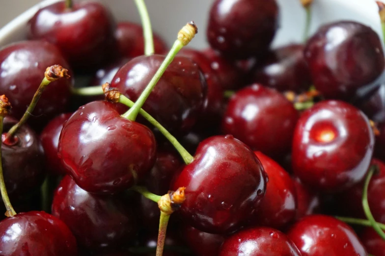 a close up of cherries in a white bowl
