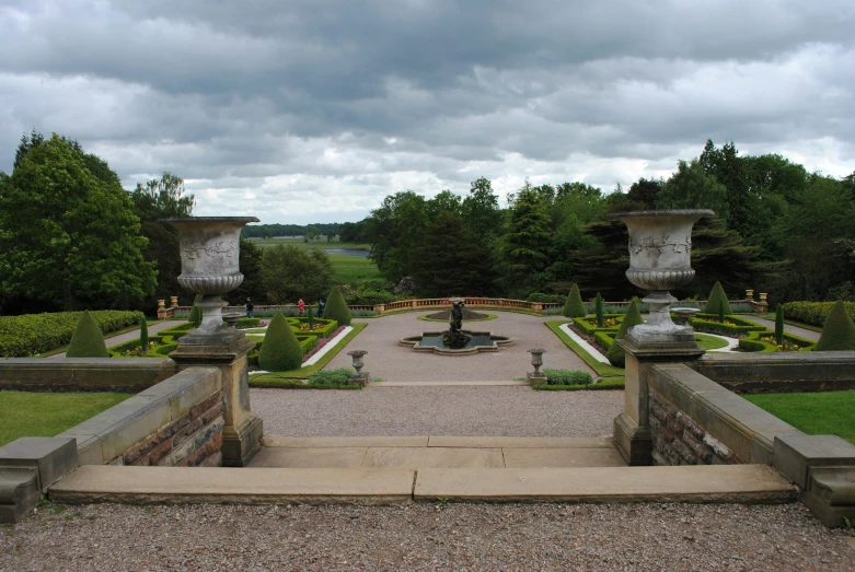 a stone path leads up to a formal garden with a fountain and landscaping