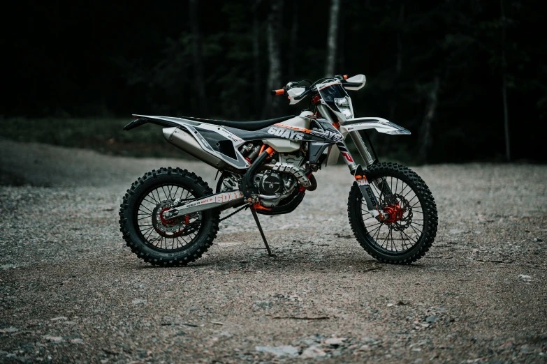 the motorcycle sits parked on a trail with lots of gravel