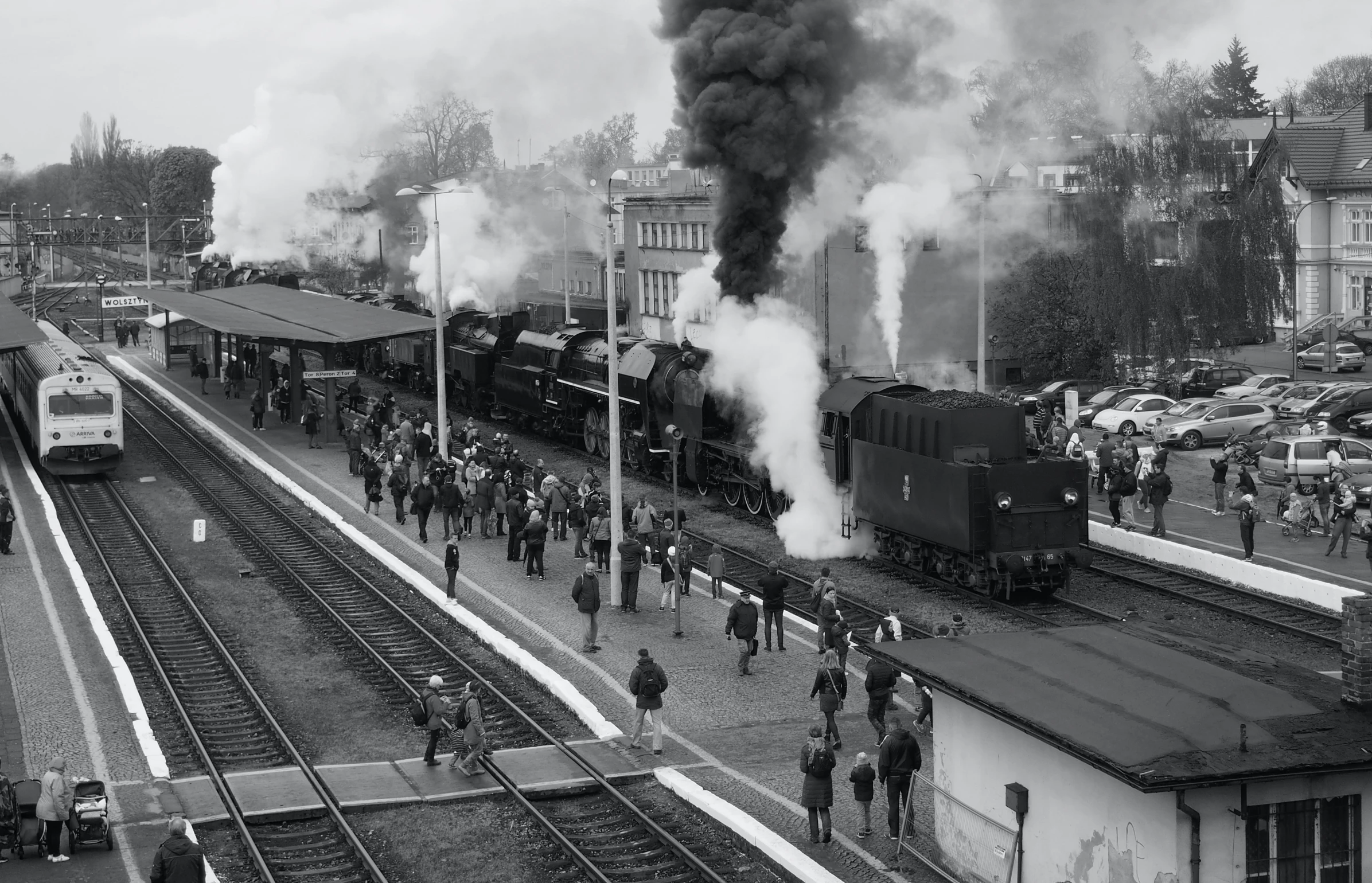 many people and a train coming down the track