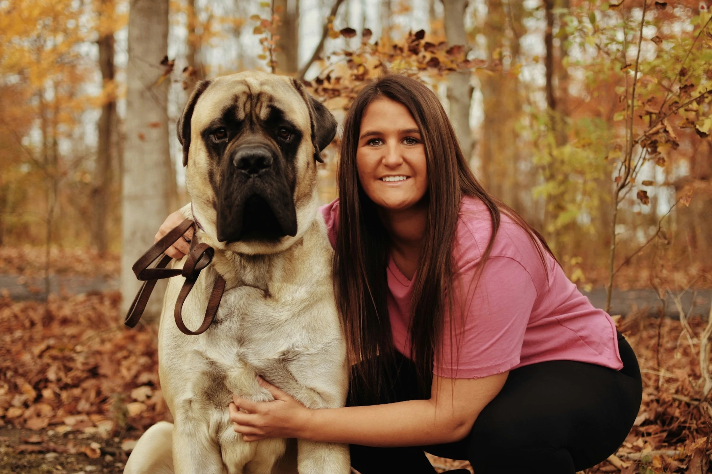 a woman kneeling down with a large dog in the woods