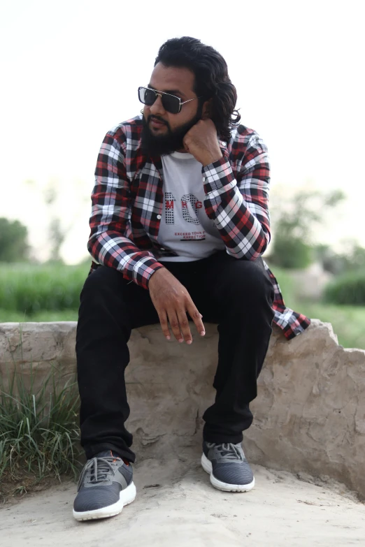 a person wearing sunglasses sitting on a ledge