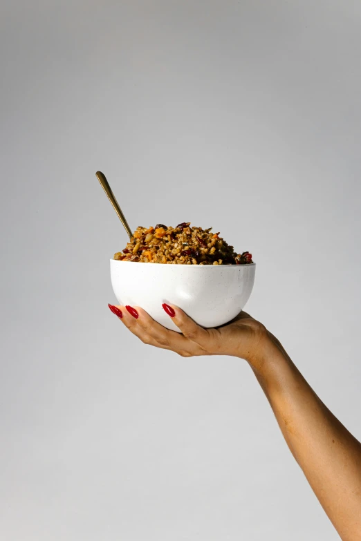 a person holding up a white bowl filled with food