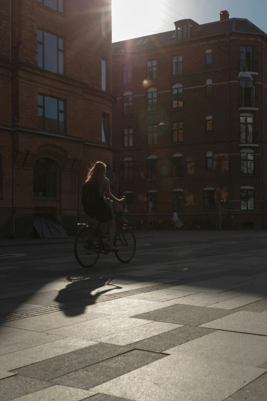 a woman riding on top of a bicycle past tall buildings