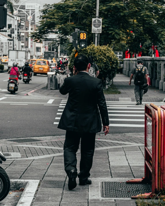 the man wearing a suit walks down a city street